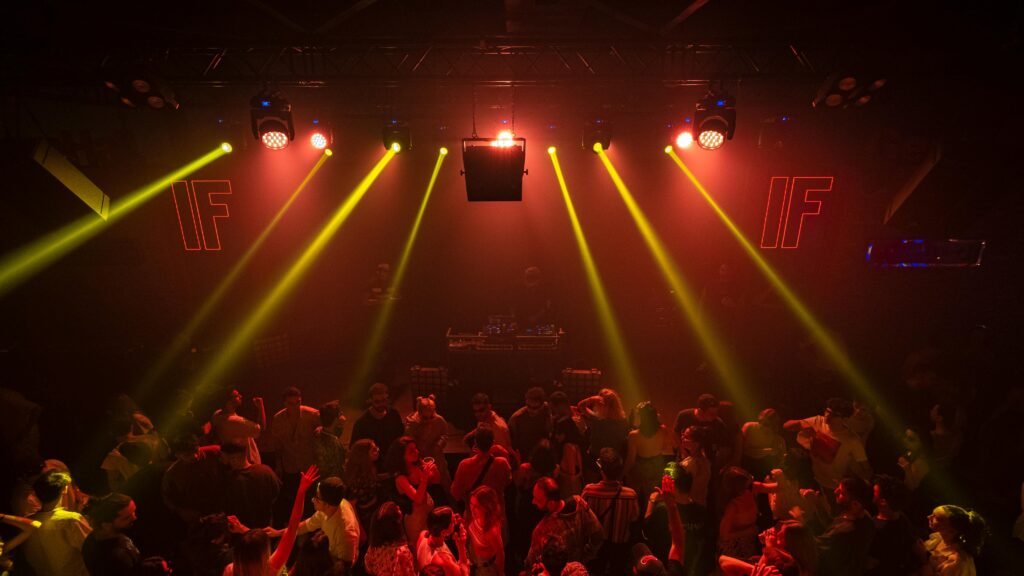 A lively nightclub scene with people dancing under red and yellow disco lights, creating a vibrant party atmosphere.