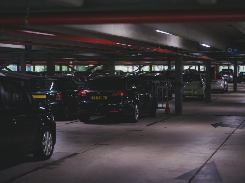 A dimly lit underground parking garage filled with parked cars and visible entrance signs.